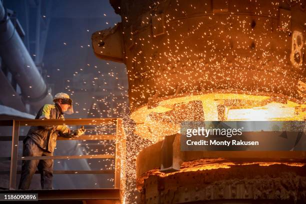 steelworker starting molten steel pour in steelworks - eisenerz stock-fotos und bilder