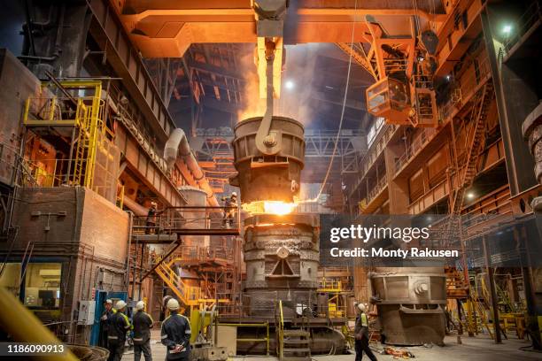 steelworkers looking on during steel pour in steelworks - metaalindustrie stockfoto's en -beelden