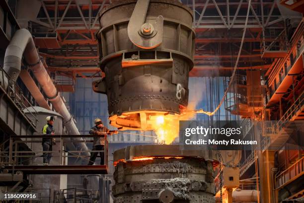 steelworker starting molten steel pour in steelworks - ijzer stockfoto's en -beelden