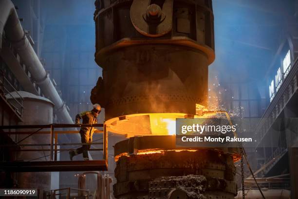 steelworker inspecting molten steel during steel pour in steelworks - mineral de hierro fotografías e imágenes de stock