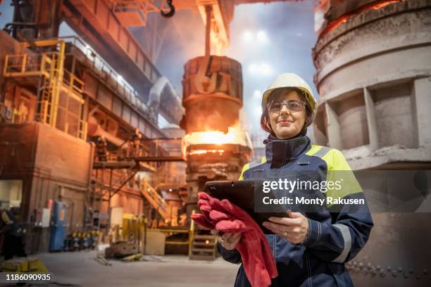 portrait of female steelworker during steel pour in steelworks - protective workwear foto e immagini stock