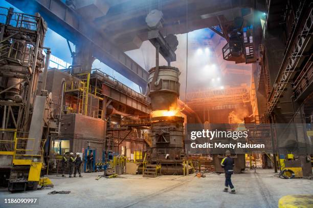 steelworkers pouring molten steel in melt shop of steelworks - siderurgicas fotografías e imágenes de stock
