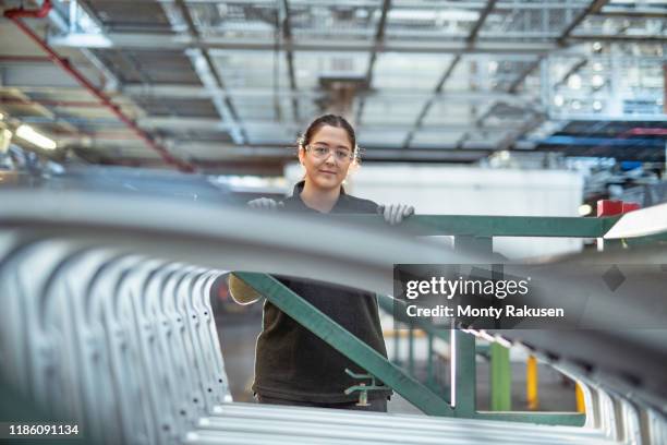 portrait of female apprentice with car parts in car factory - stage set stockfoto's en -beelden