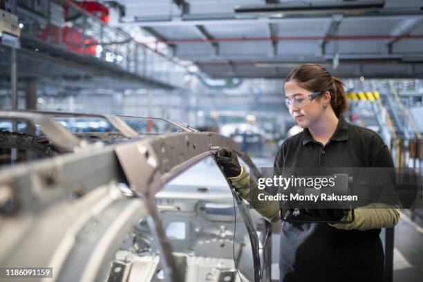 female engineer testing car body in car factory - stage set stockfoto's en -beelden