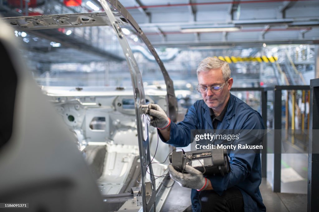 Engineer testing car body in car factory