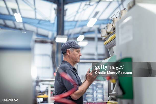 worker loading plastic packaging in print machine in print factory - printing stock-fotos und bilder