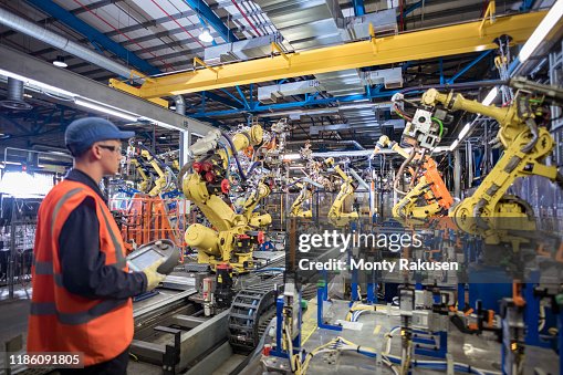 Apprentice Engineer Programming Robots In Car Factory Foto de stock ...