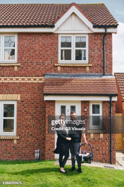 couple carrying baby in cradle in front of house - black couple standing proud uk stock pictures, royalty-free photos & images
