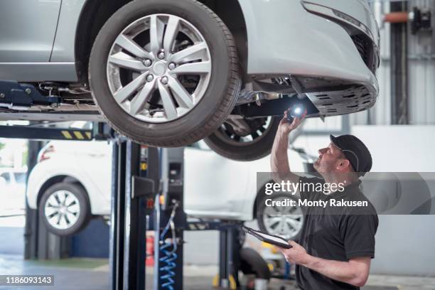 engineer checking car on ramp in car service centre - carrozzeria foto e immagini stock