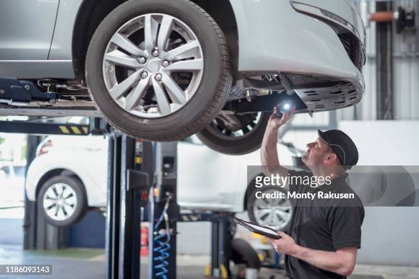 engineer checking car on ramp in car service centre - auto repair shop stockfoto's en -beelden
