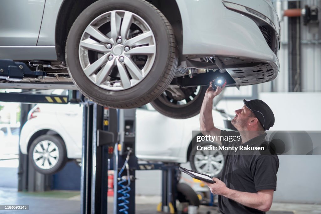 Engineer checking car on ramp in car service centre
