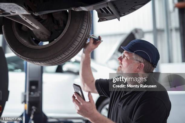 engineer checking car tyre during service in car service centre - car tyre stock-fotos und bilder