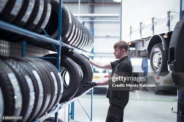 apprentice engineer selecting tyres in car service centre - autoband stockfoto's en -beelden