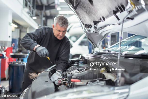 engineer checking oil level in car service centre - reparatiewerkplaats stockfoto's en -beelden