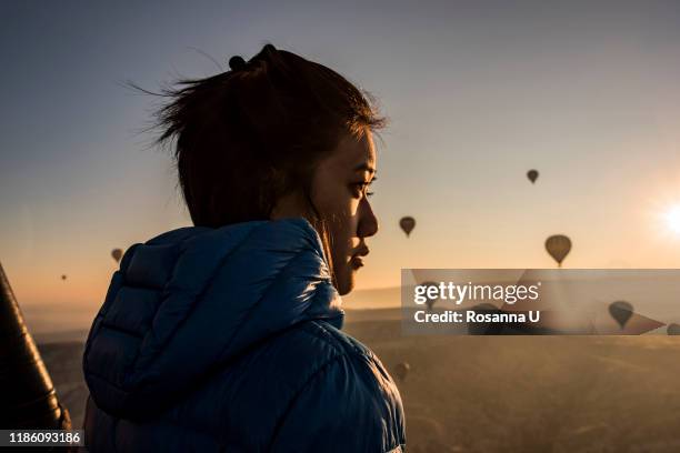 woman enjoying view, hot air balloons flying in background, göreme, cappadocia, nevsehir, turkey - hot air balloon people stock pictures, royalty-free photos & images