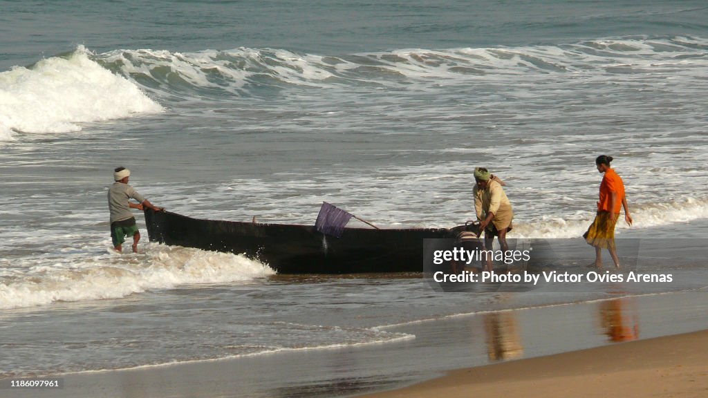 Local fishermen push their fishing boats ashore in Gokarna, Karnataka, India