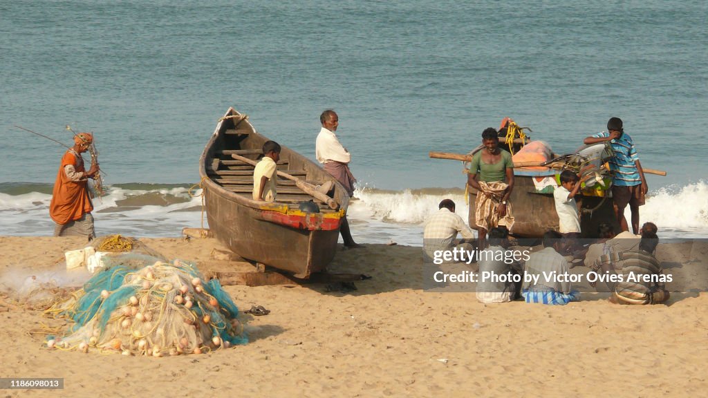 Group of local fishermen with their boats and nets on the beach in Gokarna, Karnataka, India