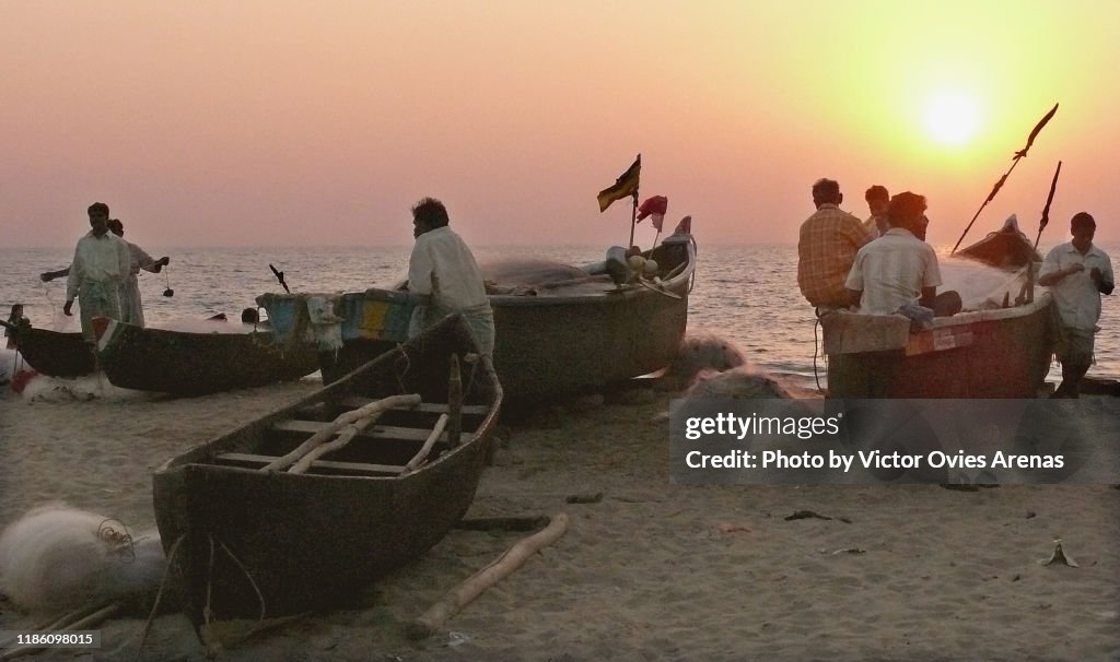 Group of local fishermen sitting on their boats at sunset on the beach in Gokarna, Karnataka, India
