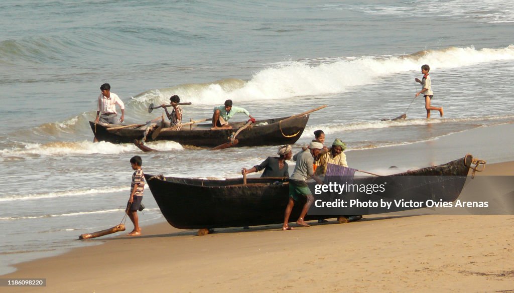 Local fishermen push their fishing boats ashore in Gokarna, Karnataka, India