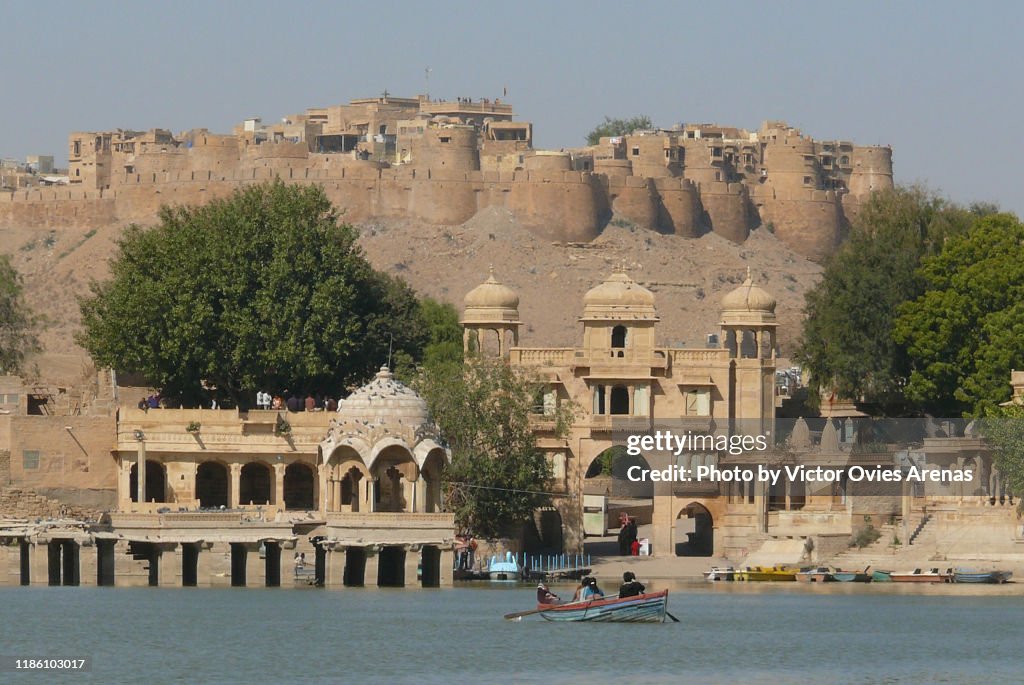 Placid boat ride with a view of Tilon-Ki-Pol gate and Jaisalmer fort from Gadi Sagar lake in Jaisalmer, Rajasthan, India