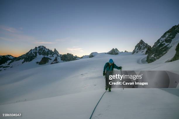 an alpinist uses a trekking pole on flat glaciated terrain pre-dawn - ski pole stock-fotos und bilder