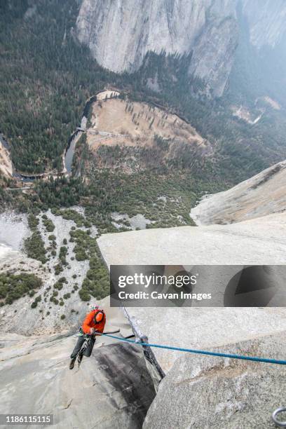 a climber ascends a rope high up on el capitan - vertige photos et images de collection