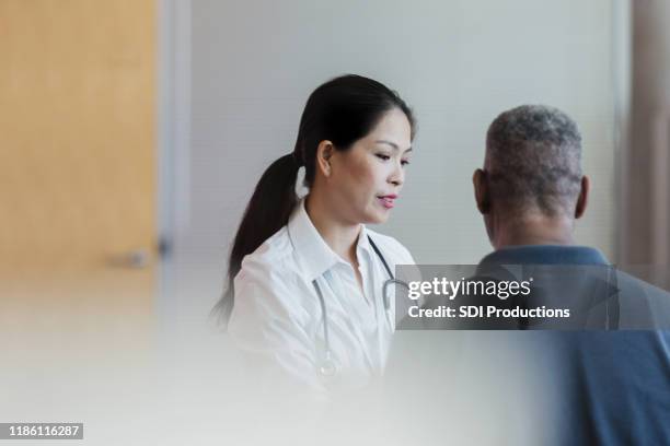 mid adult doctor and unrecognizable senior man discuss treatment options - patient hospital selective focus stock pictures, royalty-free photos & images