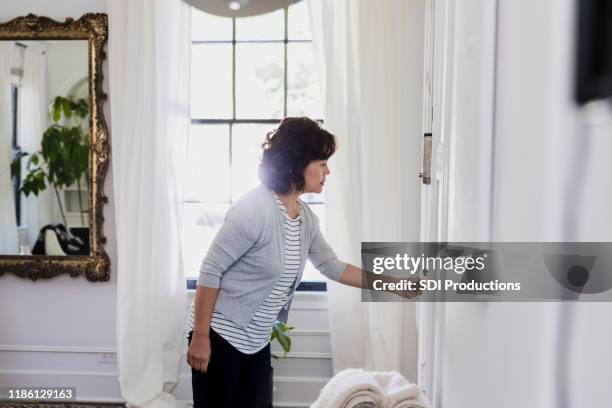 senior grandmother anticipates visit; checks front door - close stock pictures, royalty-free photos & images