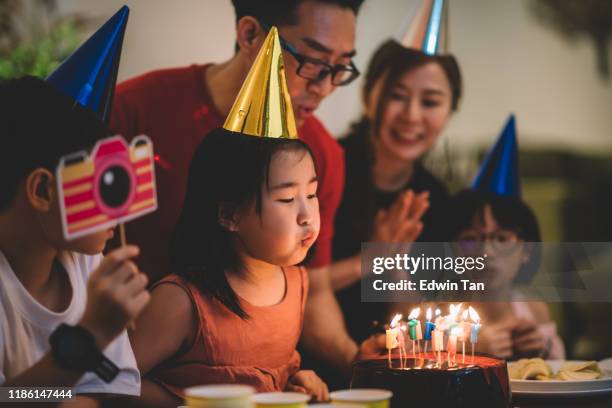 aziatische chinees gelukkig meisje blazen uit kaarsen op een verjaardagstaart - chinese birthday stockfoto's en -beelden