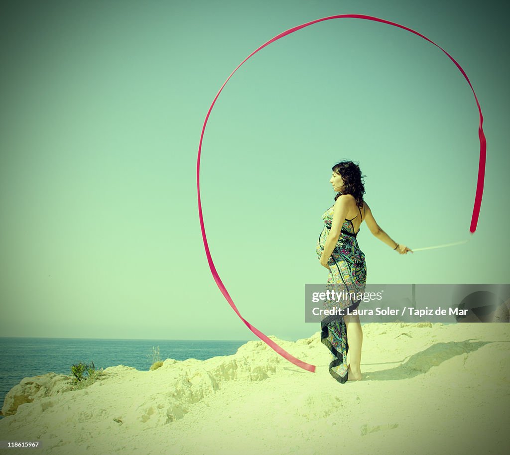 Woman standing on beach with red ribbon