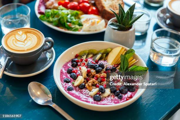 close up of healthy breakfast with acai bowl, fresh berries and fruits - acai berries stockfoto's en -beelden