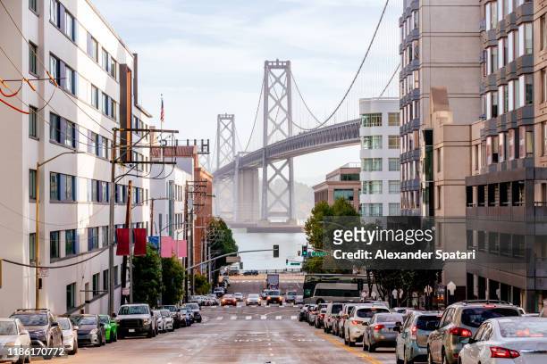 street in downtown of san francisco with san francisco-oakland bay bridge in the center, california, usa - san francisco californië stockfoto's en -beelden