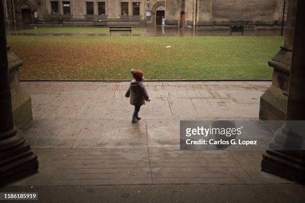 a child walks under archway in the glasgow university grounds, scotland, united kingdom - glasgow university stock pictures, royalty-free photos & images