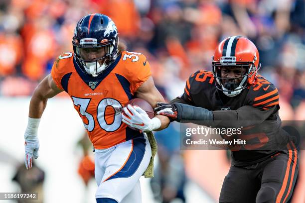 Phillip Lindsay of the Denver Broncos runs the ball and breaks the tackle attempt of Jermaine Whitehead of the Cleveland Browns at Broncos Stadium at...