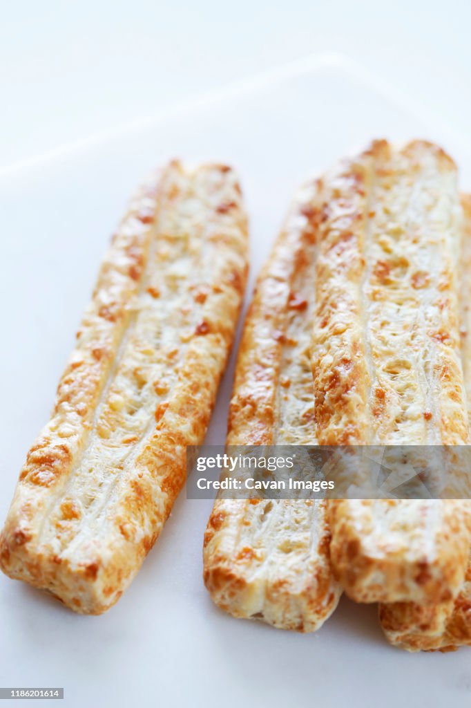 High angle close-up of cheese sticks served in plate on white background