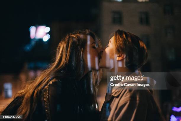 lesbian couple kissing in city at night - first kiss imagens e fotografias de stock