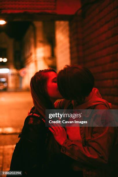 lesbian couple kissing in city at night - photos of lesbians kissing stock pictures, royalty-free photos & images