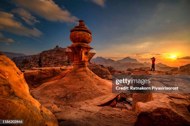 photographer standing on top of petra monastery at sunset, petra, jordan, in the ancient nabbatean city of petra in jordan at sunset with a view to the city of wadi musa. - petra fotografías e imágenes de stock