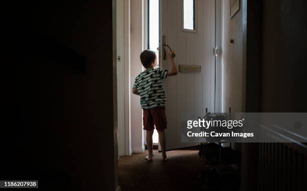 rear view of boy looking through doorway while standing at home - open day 6 stock pictures, royalty-free photos & images