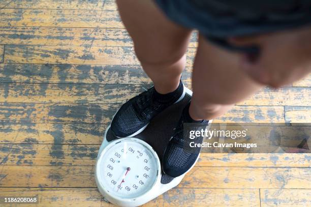 low section of man checking weight on scale in gym - báscula de baño fotografías e imágenes de stock