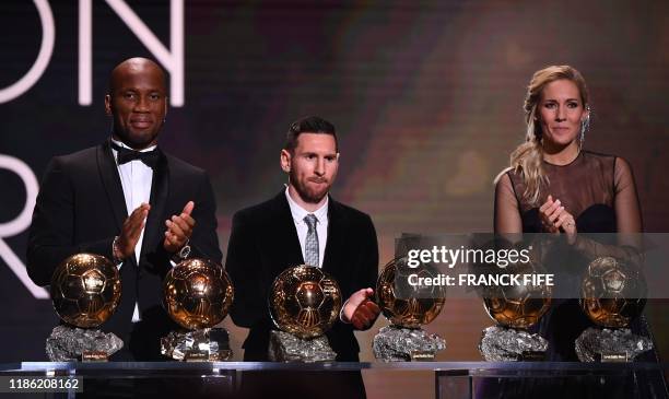 Barcelona's Argentinian forward Lionel Messi reacts after winning the Ballon d'Or France Football 2019 trophy between Former Ivorian forward Didier...