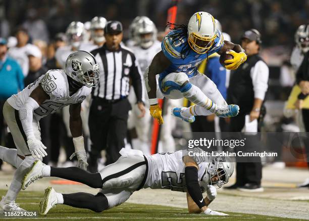 Melvin Gordon of the Los Angeles Chargers jumps over Erik Harris of the Oakland Raiders in the second quarter at RingCentral Coliseum on November 07,...