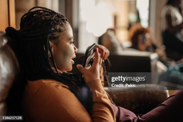 african woman sending voice message on mobile phone - voice command stock pictures, royalty-free photos & images