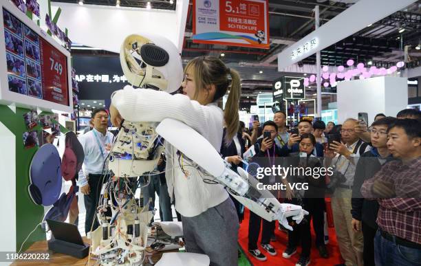 Woman hugs an Infineon Roboy robot, the 749th hug the Roboy has received during the 2nd China International Import Expo at the National Exhibition...