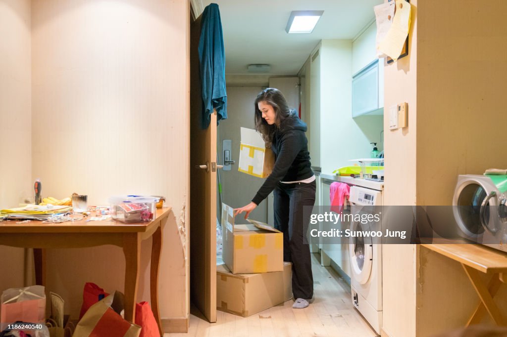 Woman packing belongings in cardboard boxes, moving house