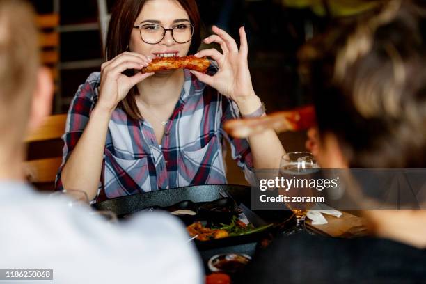young woman in a pub enjoying sparerib held in hands - costeleta comida imagens e fotografias de stock