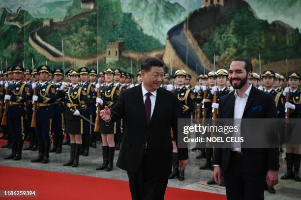 China's President Xi Jinping walks with El Salvador's President Nayib Bukele after inspecting an honour guard during a welcoming ceremony at the...