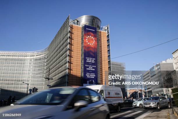 Cars drive past the European Commission headquarters with a new banner with the lettering reading 'For a union that strives for more' in different...