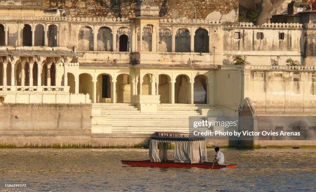 Traditional boat on lake Pichola and the empty ghats at sunset in Udaipur, Rajasthan, India