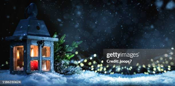 christmas lantern with lit candle on snow - snowfall and lights night defocussed stock pictures, royalty-free photos & images